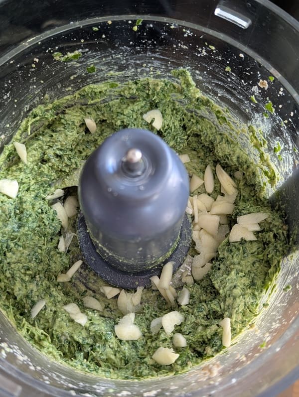 Ajout de l'ail haché à la préparation et mixage final pour obtenir une texture de pesto homogène