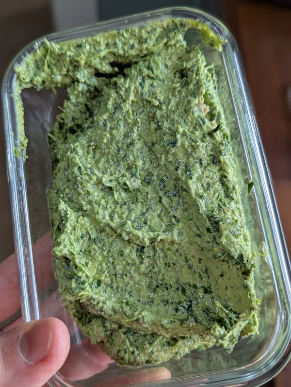 Pesto de roquette healthy fait maison présenté dans une boîte hermétique avant d'être placé au réfrigérateur
