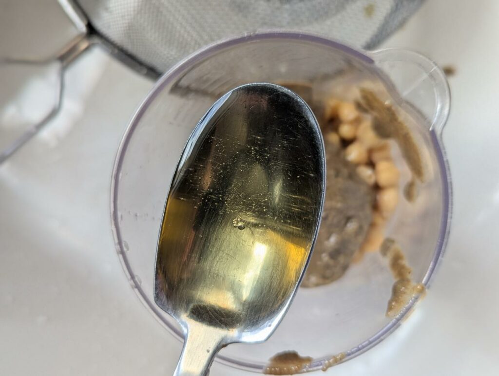 Cuillère de sirop d'agave versée dans le bol des pois chiches