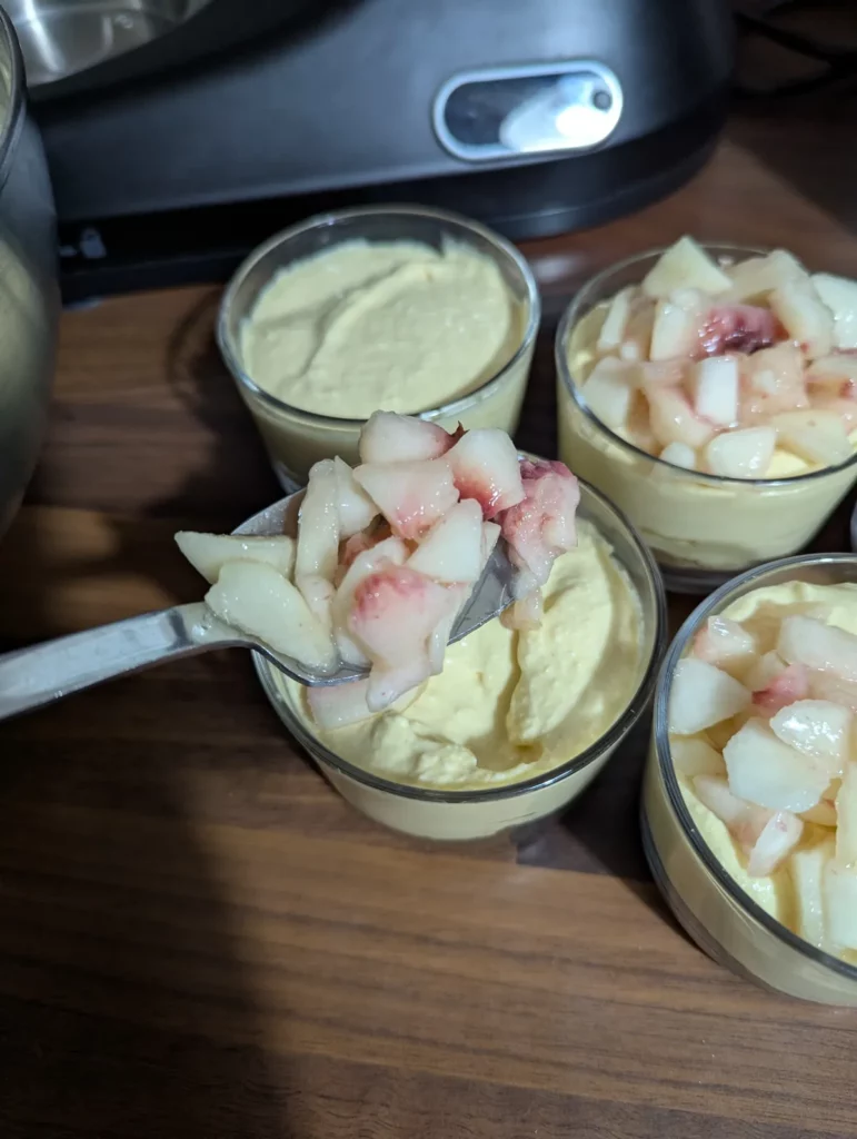 Morceaux de pêche déposés à la cuillère sur la crème au mascarpone