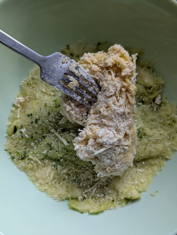 Courgette râpée bien essorée ajoutée au mélange dans le saladier, prête à être incorporée.