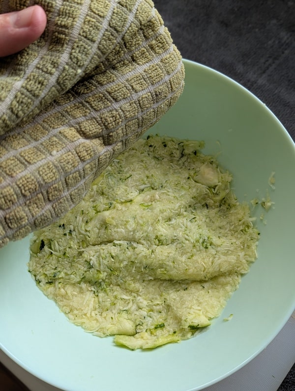 Courgette râpée pressée dans un torchon propre pour en extraire l’eau.