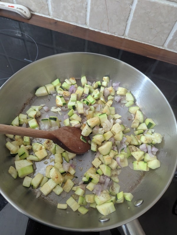 Des cubes de courgettes en train de griller dans une poêle, ajoutant une texture et une saveur délicieuse au risotto.
