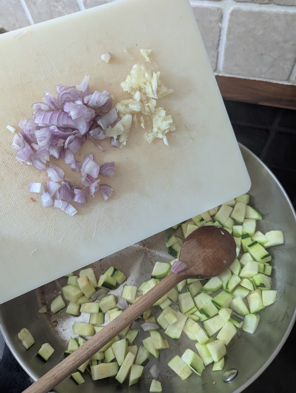 Dés de courgettes avec l’oignon et l’ail dans la poêle, cuisson des légumes pour ce risotto