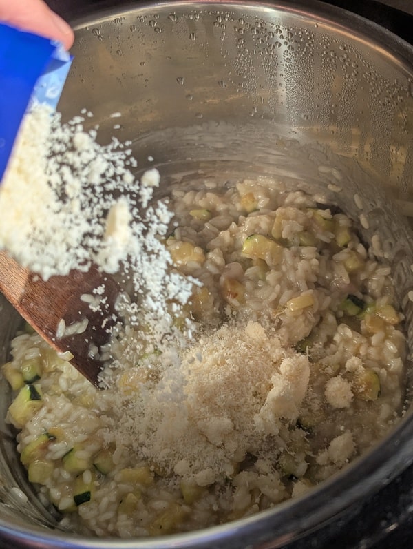 Parmesan ajouté au risotto aux courgettes hors du feu pour la finalisation.