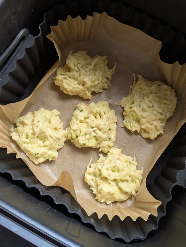 Petits tas de pâte formés à la cuillère et légèrement aplatis sur une feuille de papier cuisson.