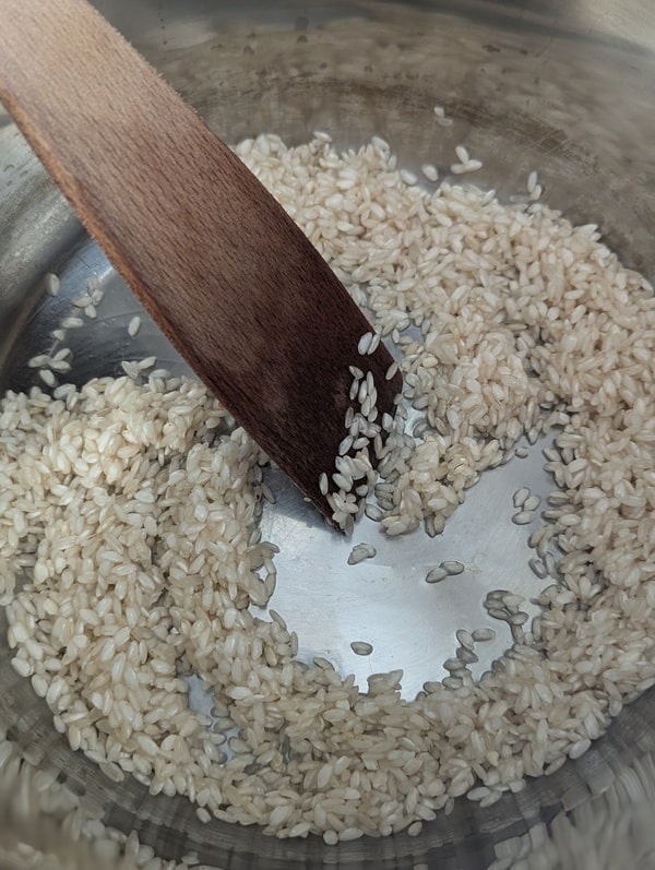 Riz arborio nacrant dans la poêle, étape clé pour un risotto parfait