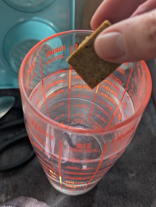 Un cube de bouillon déposé dans de l’eau chaude, préparant le liquide essentiel pour un risotto riche en saveurs.