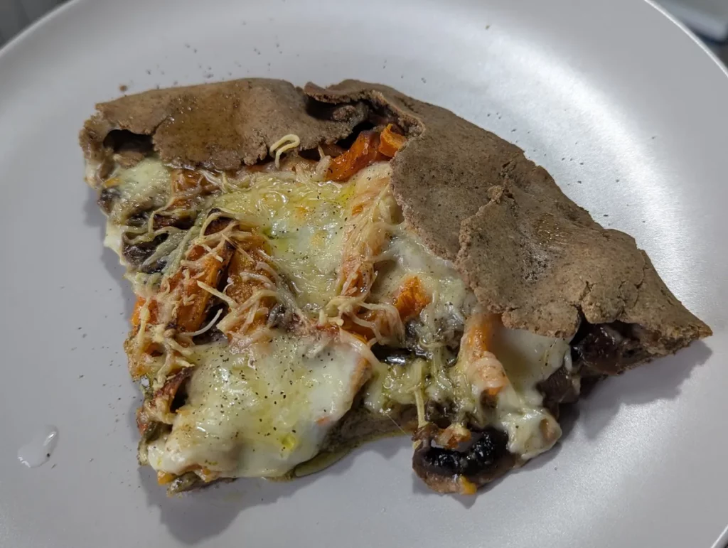 Part de pizza sans gluten au sarrasin garnie de légumes et fromage fondu