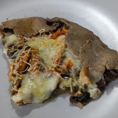 Part de pizza sans gluten au sarrasin garnie de légumes et fromage fondu